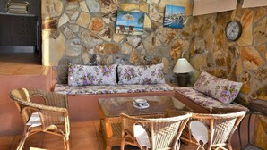 A cozy living area with a stone wall, wicker furniture, and a glass coffee table.