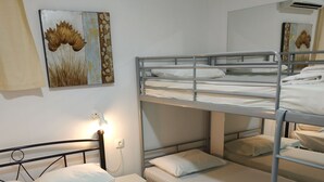 Een slaapkamer met stapelbed, witte beddengoed en een bedlampje.