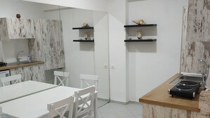 Een moderne keuken met witte kasten, een eettafel met stoelen en een inbouwfornuis.