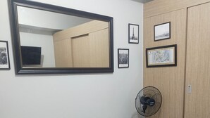 A bedroom with a bed, a black leather sofa, a standing fan, and a wardrobe. - Beautiful Condominium With Swimming Pools Ect (Quezon City)
