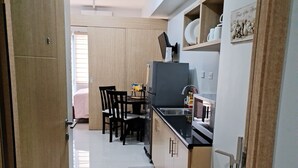 A modern kitchen with wooden cabinets, a black countertop, and a dining area with chairs and a table. - Beautiful Condominium With Swimming Pools Ect (Quezon City)