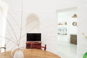 Relax in this serene living space with a dining table, TV, and stylish shelf.