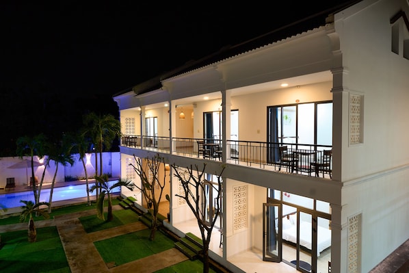A multi-story hotel with balconies, a swimming pool, and a well-lit interior. - Tran Family Villas Boutique Hotel (Da Nang)