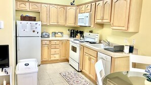 Una cucina funzionale con mobili in legno, un frigorifero, un forno a microonde, un piano cottura e un lavello.