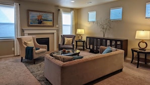 A living room with a beige sofa, two armchairs, a coffee table, a fireplace, and a painting on the wall. - Spacious 3-bedroom home with outdoor space (Eugene)