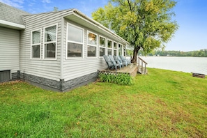 A house with a covered porch, a large window, and a view of a lake. - Pratt Lake Peninsula: Summer on Pratt Lake • Kayaks Included • Dog Friendly (Gladwin)