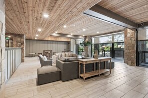 A spacious indoor area with a wooden ceiling, a stone wall, and a seating area with a sofa and a table. - Blackstone Flats 210 (Park City)
