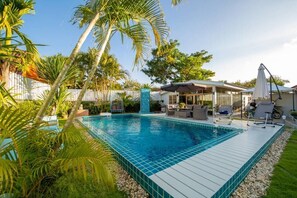 Relax by the pool surrounded by lush greenery and palm trees.
