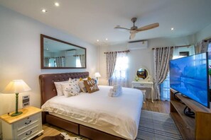 Relax in comfort with a large bed, TV, and ceiling fan.