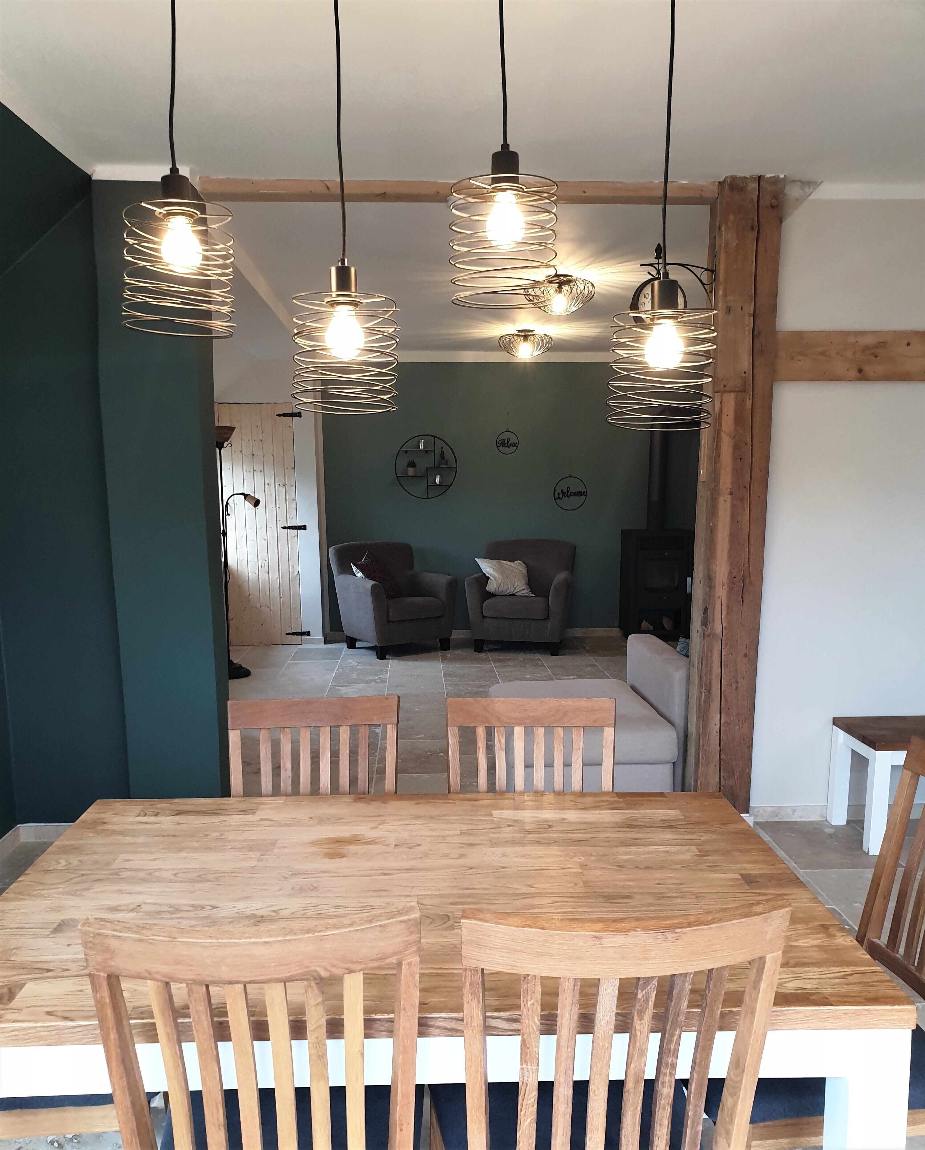 Un comedor con una mesa y sillas de madera, techo de madera y luces colgantes.