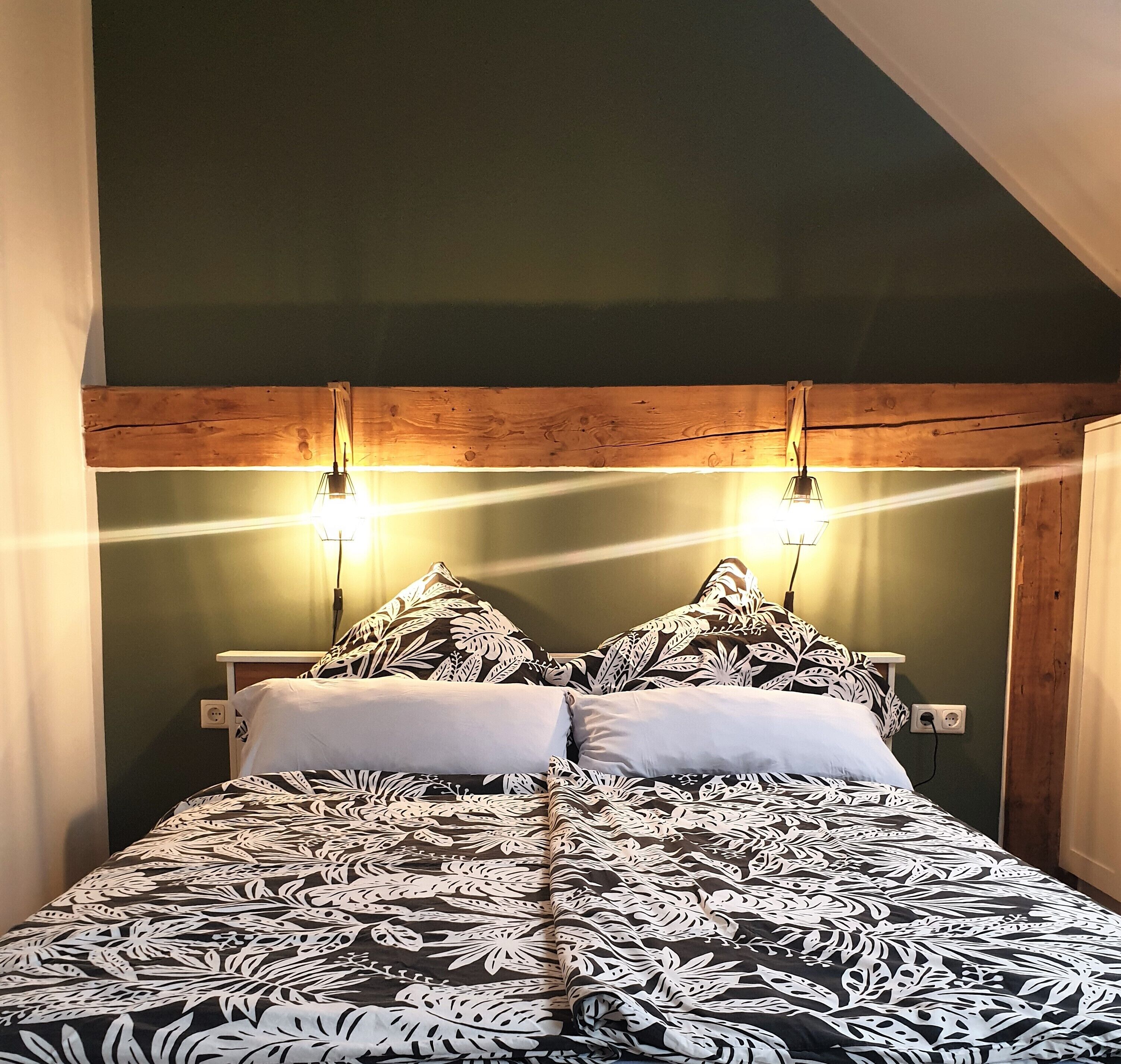 Un dormitorio con cama, dos lámparas de noche y cabecera de madera.