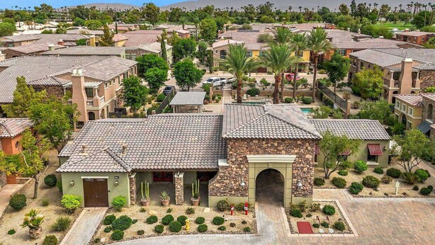 A residential area with terracotta-tiled houses, a central courtyard with cacti, and a mountain in the background. - Luxury Tuscan Condo in the Heart of Palm Desert! (Palm Desert)
