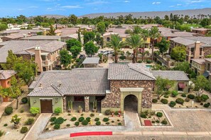 A residential area with terracotta-tiled houses, a central courtyard with cacti and shrubs, and a mountain range in the background.