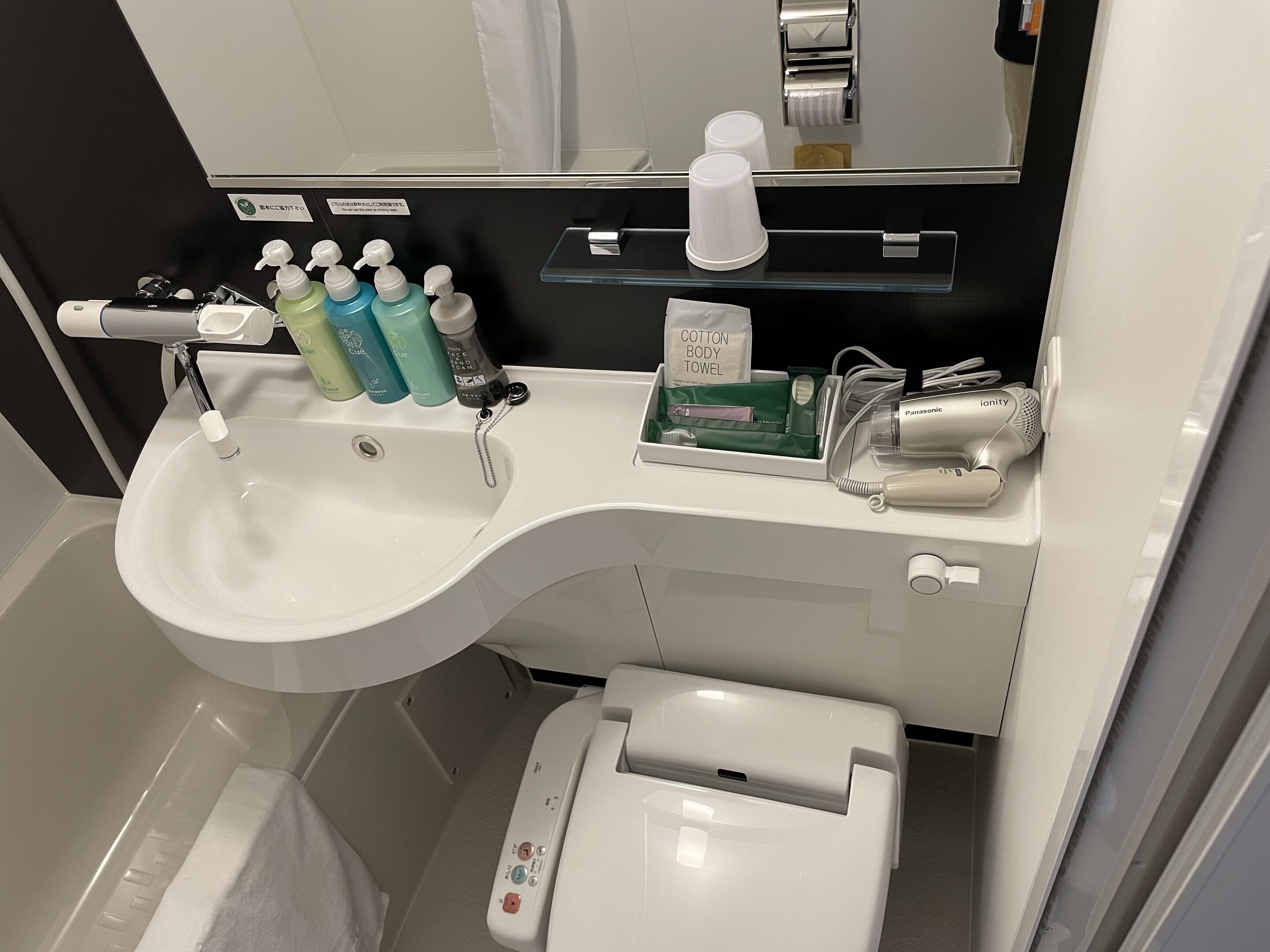 Un bagno con un lavandino bianco, uno specchio, un portascopevoli e un water.