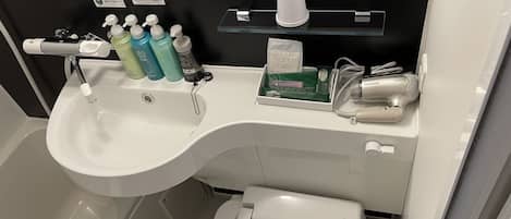 Un baño con lavamanos blanco, un espejo, toallero y un inodoro.