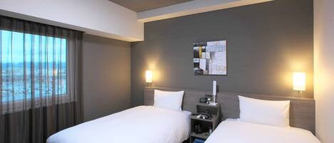 A hotel room with two beds, a nightstand, a lamp, a painting on the wall, and a window with curtains.