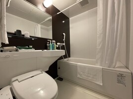 Bañera con ducha, pantuflas, toallas