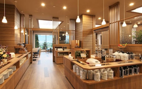 A modern hotel lobby with wooden flooring, a central reception desk, and a view of the outdoors.