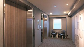 Un moderno ascensor con paneles de madera, una pequeña zona de estar con dos sillas y una mesa, y un ventanal con vistas.