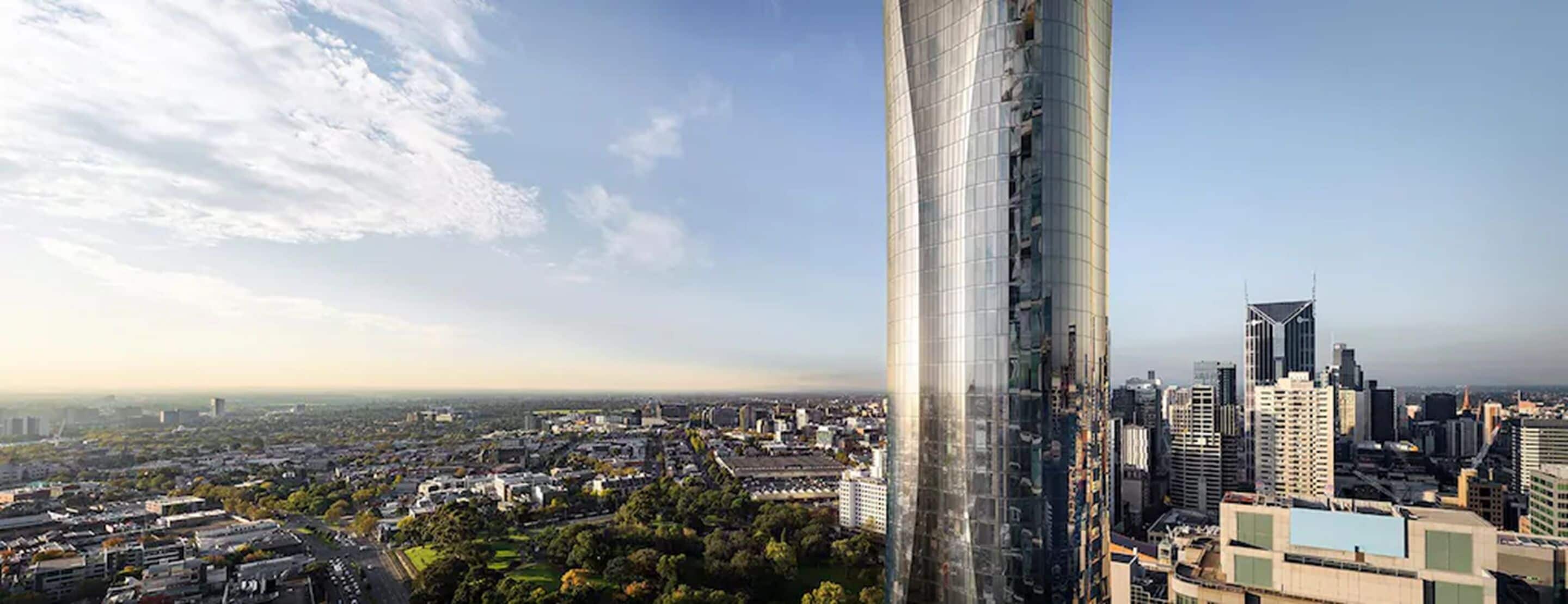 Ein Hochhaus mit Glasfassade, umgeben von einer Stadtlandschaft mit verschiedenen Gebäuden und blauem Himmel.