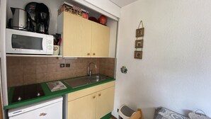 A compact kitchen with a microwave, coffee maker, and cabinets. - Studio for 4 near shops, 450 m to slopes (Les Carroz d'Arâches)