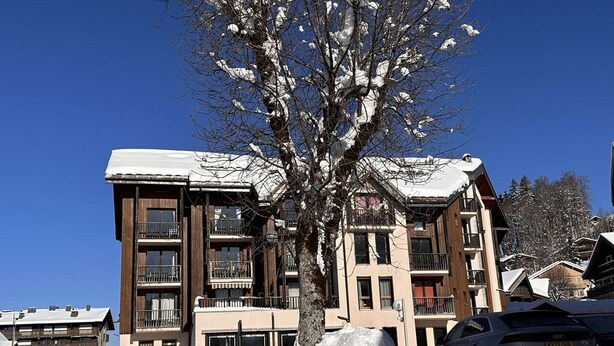 A multi-story building with balconies, snow-covered roofs, and a tree in front. - Studio for 4 near shops, 450 m to slopes (Les Carroz d'Arâches)