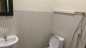 Pieni kylpyhuone, jossa on wc, pesuallas ja suihku.