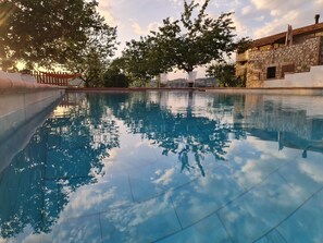 A swimming pool with clear water reflecting trees and a stone building in the background. - Villa Graziella, Romantic Perugia  (La Valle)