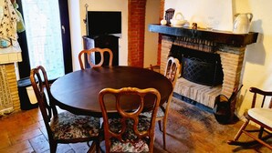 Un comedor con una mesa redonda, cuatro sillas, una chimenea y un televisor.