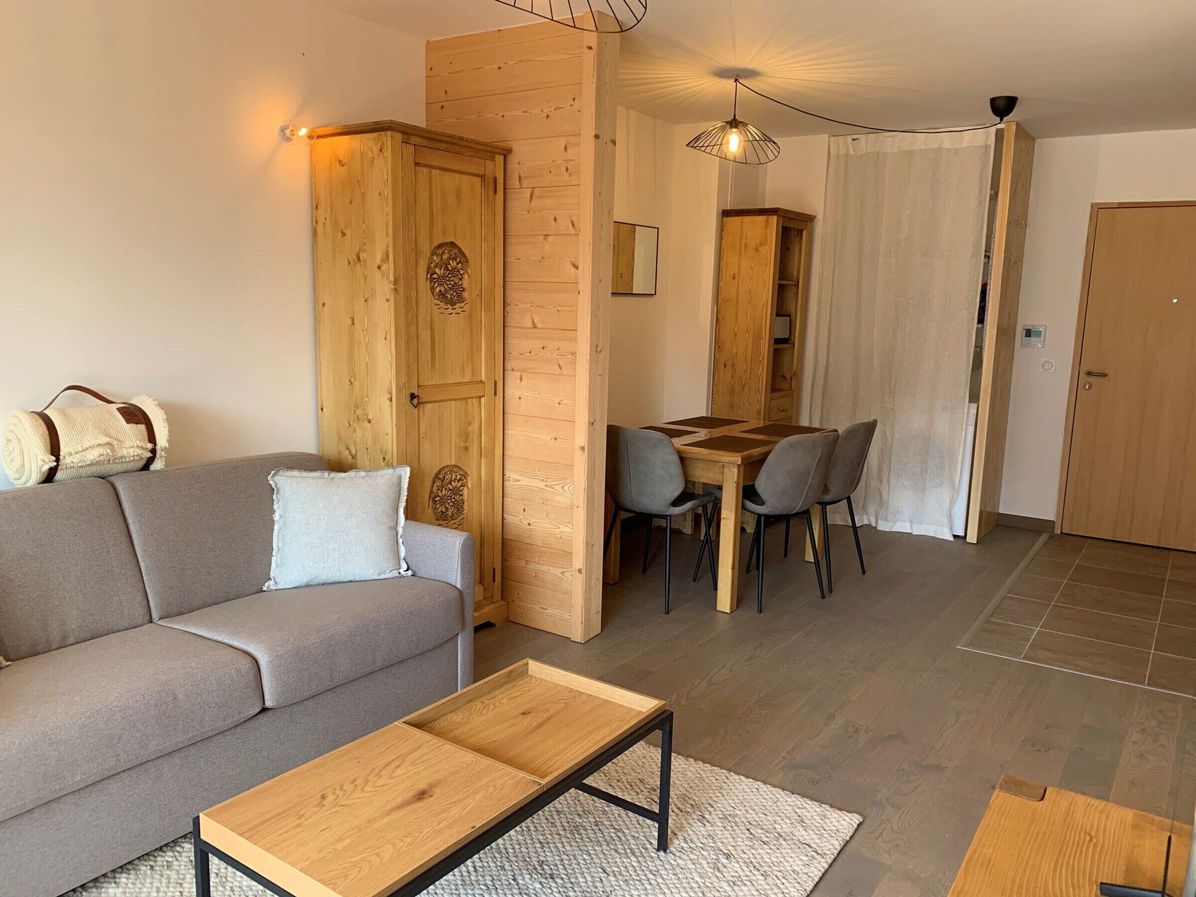 A modern living room with a sofa, a wooden coffee table, and a dining area with a table and chairs.