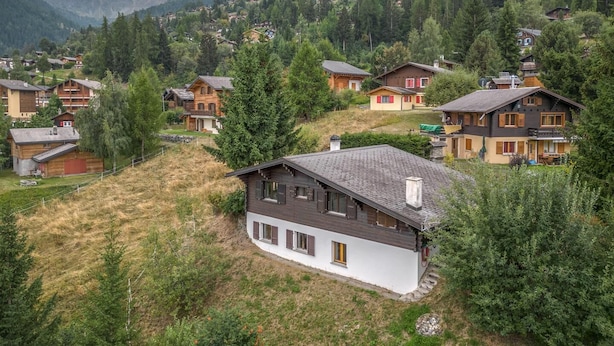 Een dorpje omgeven door dichte bossen en heuvels, met traditionele houten huizen.
