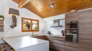 Een moderne keuken met een marmeren eiland, houten kasten en een ingebouwde oven.
