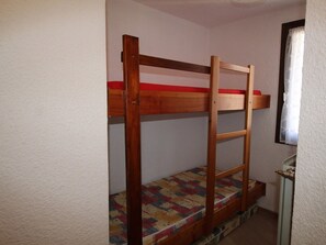 Uma cama beliche com estrutura de madeira e colchão colorido.