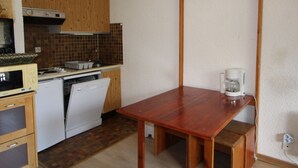A compact kitchen with wooden cabinets, a microwave, a dishwasher, and a coffee maker on a wooden table.