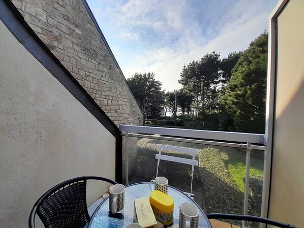 Enjoy the serene views of the lush landscape from this balcony with a glass table and comfortable chair.