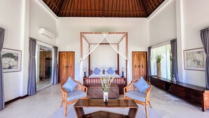 A spacious room with a large bed, two wooden chairs, a coffee table, and a canopy bed. - The Backyard Bingin - Cliff Top 10 bedroom Private Villa by Bingin Beach (Pecatu,)