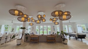 A spacious indoor area with multiple hanging wicker light fixtures, a pool table, and a seating area with white chairs and a sofa. - The Backyard Bingin - Cliff Top 10 bedroom Private Villa by Bingin Beach (Pecatu,)