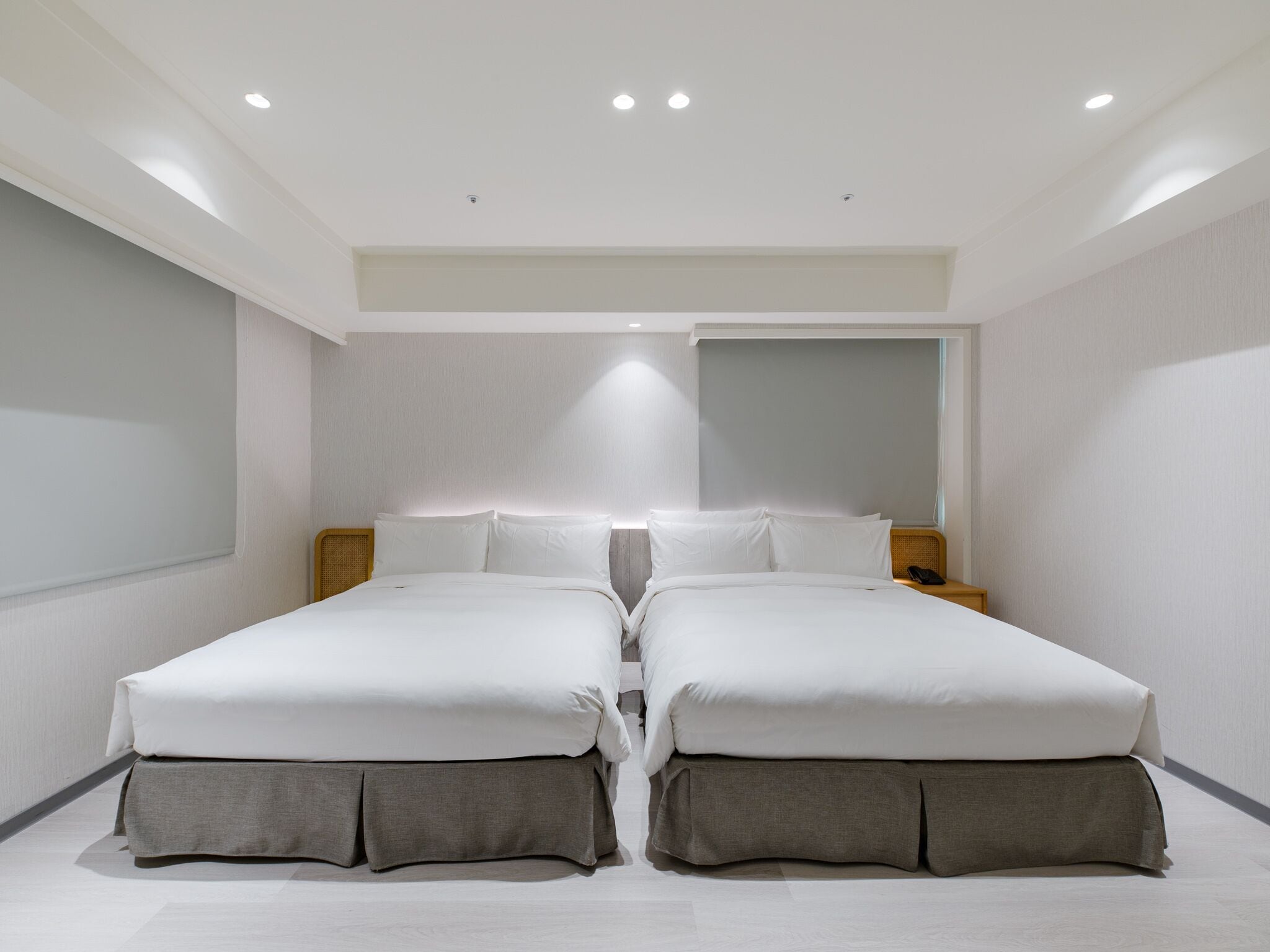 A modern hotel room with two beds, a large mirror, and recessed ceiling lighting.