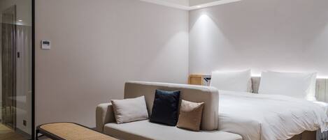 A modern hotel room with a bed, a sofa, and a small table.