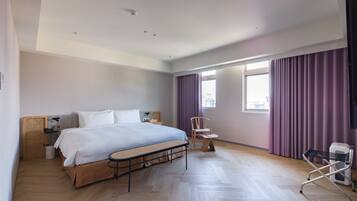 A modern hotel room with a large bed, a small table, a chair, and a TV.