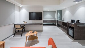 A modern hotel room with a flat-screen TV, a dining area with a table and chairs, a kitchenette, and a sofa. - DAHU Park Hotel (Taipei)