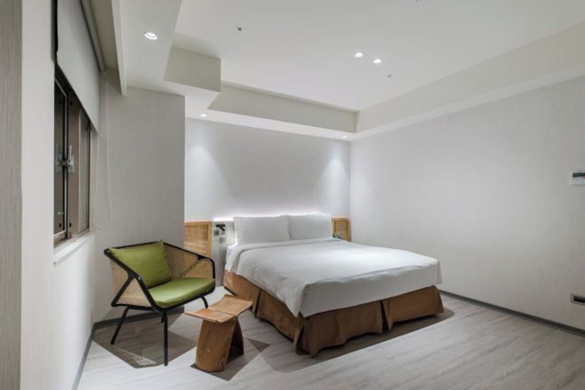 Un dormitorio moderno con una cama, una silla y una mesita de noche.