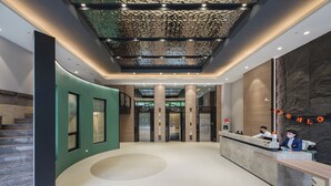 A modern hotel lobby with a reception desk, elevators, and a unique ceiling design. - DAHU Park Hotel (Taipei)