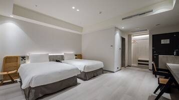 A modern hotel room with two beds, a desk, and a chair.