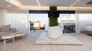 A modern living room with a sofa, two side tables, a white coffee table, a large white rug, and a green vertical garden. - Incanto Suites - Mets (Athens)