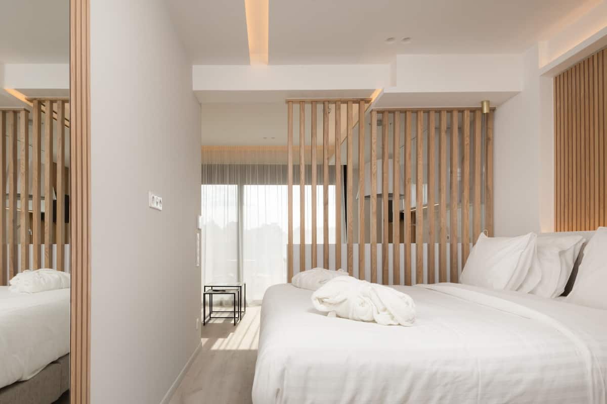 Un hotel moderno con una cama grande, una mesita y vistas de la ciudad a través de amplios ventanales.