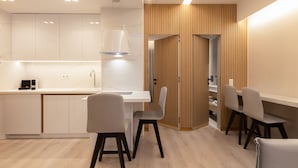 A modern kitchen with white cabinets, a marble countertop, and a pendant light. There is a dining area with two chairs and a table. - Incanto Suites - Mets (Athens)