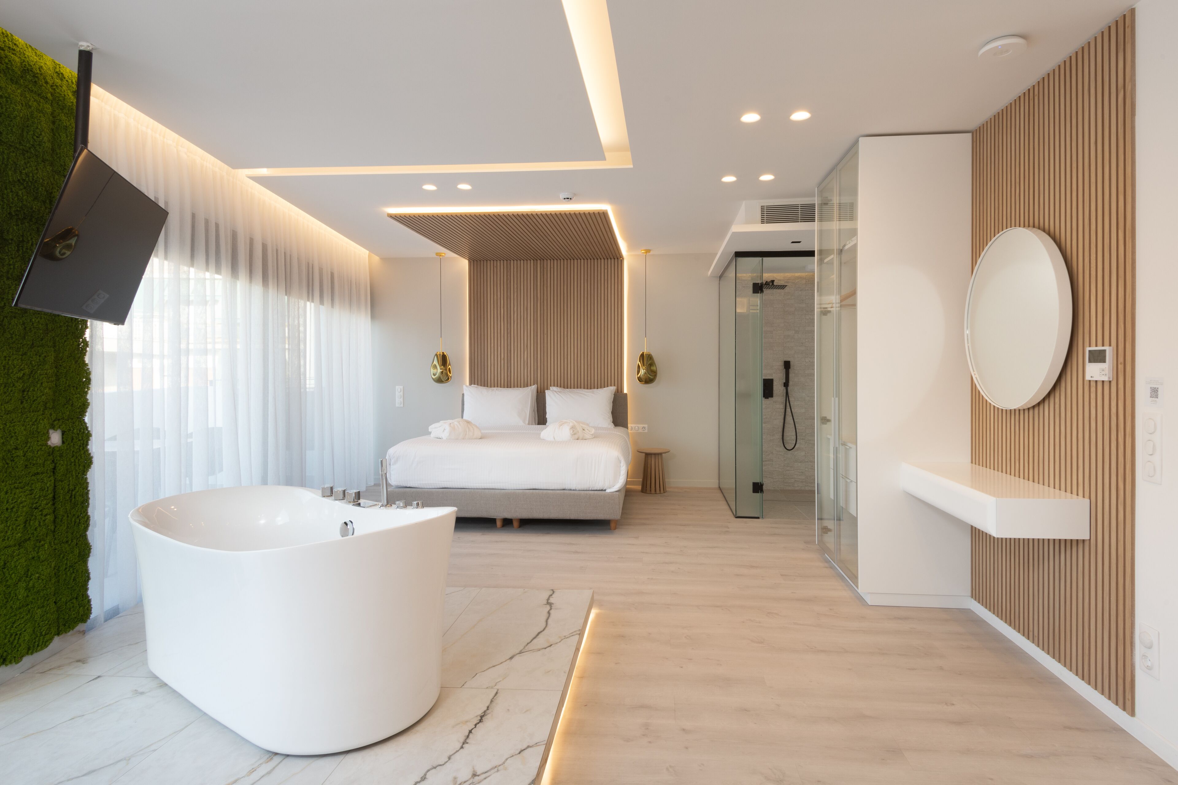 Un dormitorio moderno con una cama grande, una bañera independiente y un box de ducha de cristal.