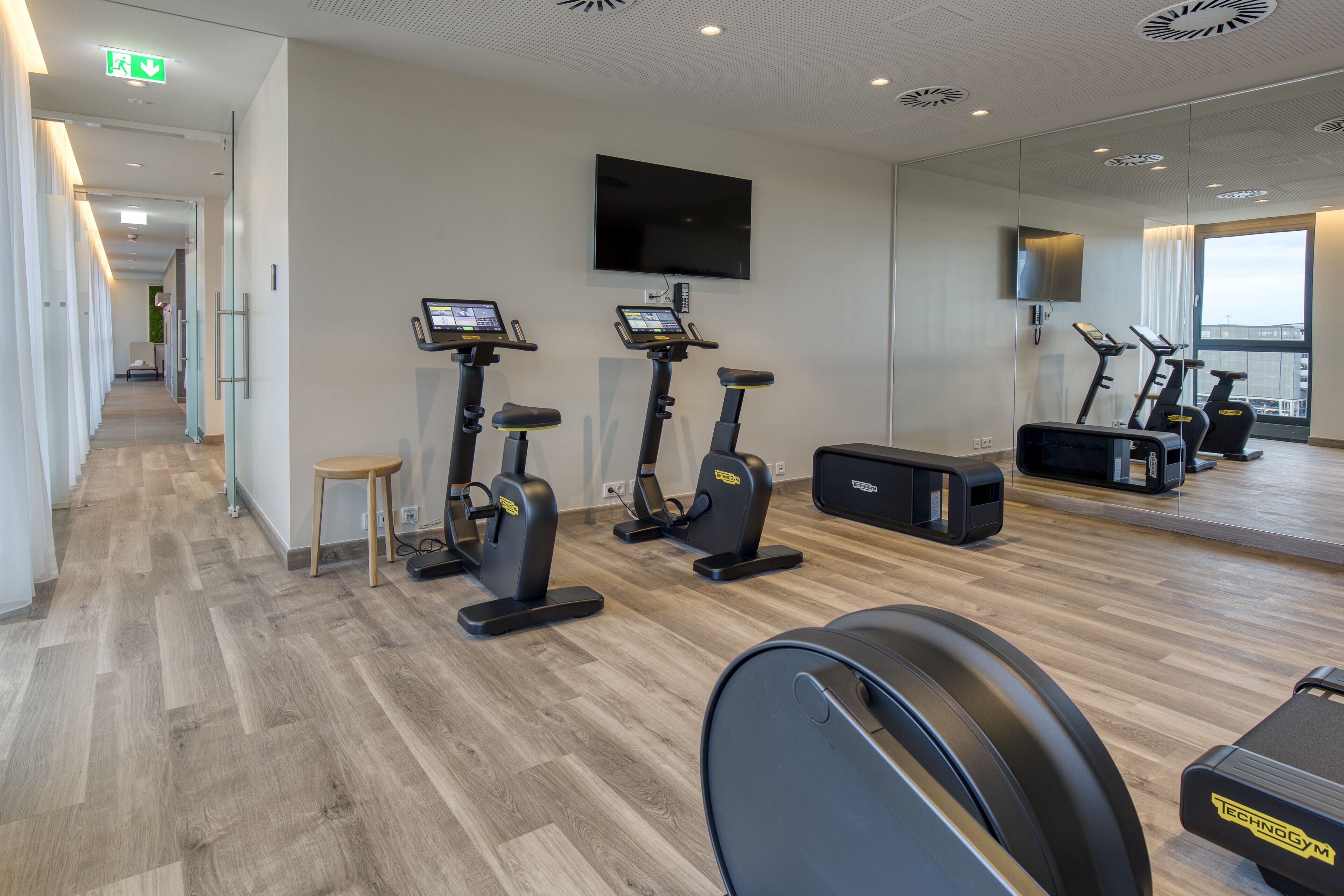 Un gimnasio con cintas de correr, bicicletas estáticas y un espejo grande.