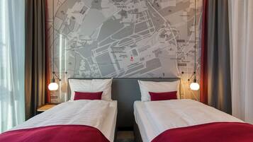 Habitación de hotel con dos camas, un mapa en la pared y vistas a la ciudad.